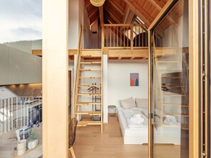 Ein modernes Interieur mit Schlafzimmer im oberen Bereich, einer Treppe und einem Balkon.