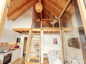Ein Schlafzimmer im Loft-Stil mit einer Holztreppe und einer Erschliessungsebene.
