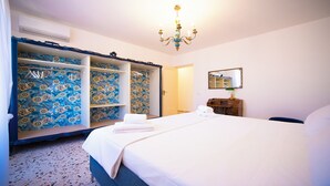 A bedroom with a bed, a wardrobe with floral wallpaper, a chandelier, a mirror, and a dresser. - Solemar Sicilia - Stella Marina (Santa Flavia)