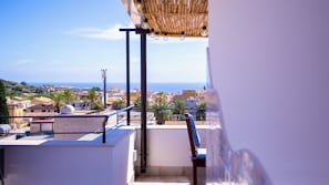 Ein Balkon mit Blick auf eine Küstenstadt, eine Pergola mit hängenden Lichtern und ein Metallgeländer.