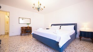 A bedroom with a bed, a desk, a chair, a mirror, and a chandelier. - Solemar Sicilia - Stella Marina (Santa Flavia)
