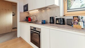 Ett modernt kök med vita skåp, en inbyggd ugn, en mikrovågsugn och en kaffebryggare.