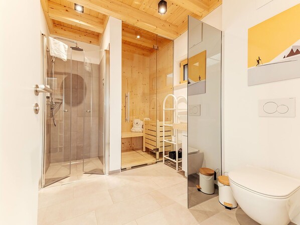 Ein modernes Badezimmer mit Duschkabine aus Glas, Holzboden und weißer Toilette.