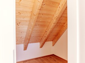 Ein Zimmer mit schrägverdeckter Holzbalkendecke und Holzboden.
