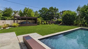 A swimming pool with a clear blue water surface, surrounded by a well-maintained lawn and a modern outdoor structure. - Modern house for 7 with heated pool (Arradon)