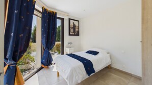 A bedroom with a bed, a nightstand, a window with curtains, and a framed picture on the wall. - Modern house for 7 with heated pool (Arradon)