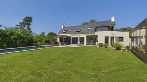 A modern two-story house with a swimming pool, a covered patio, and a well-maintained lawn. - Modern house for 7 with heated pool (Arradon)