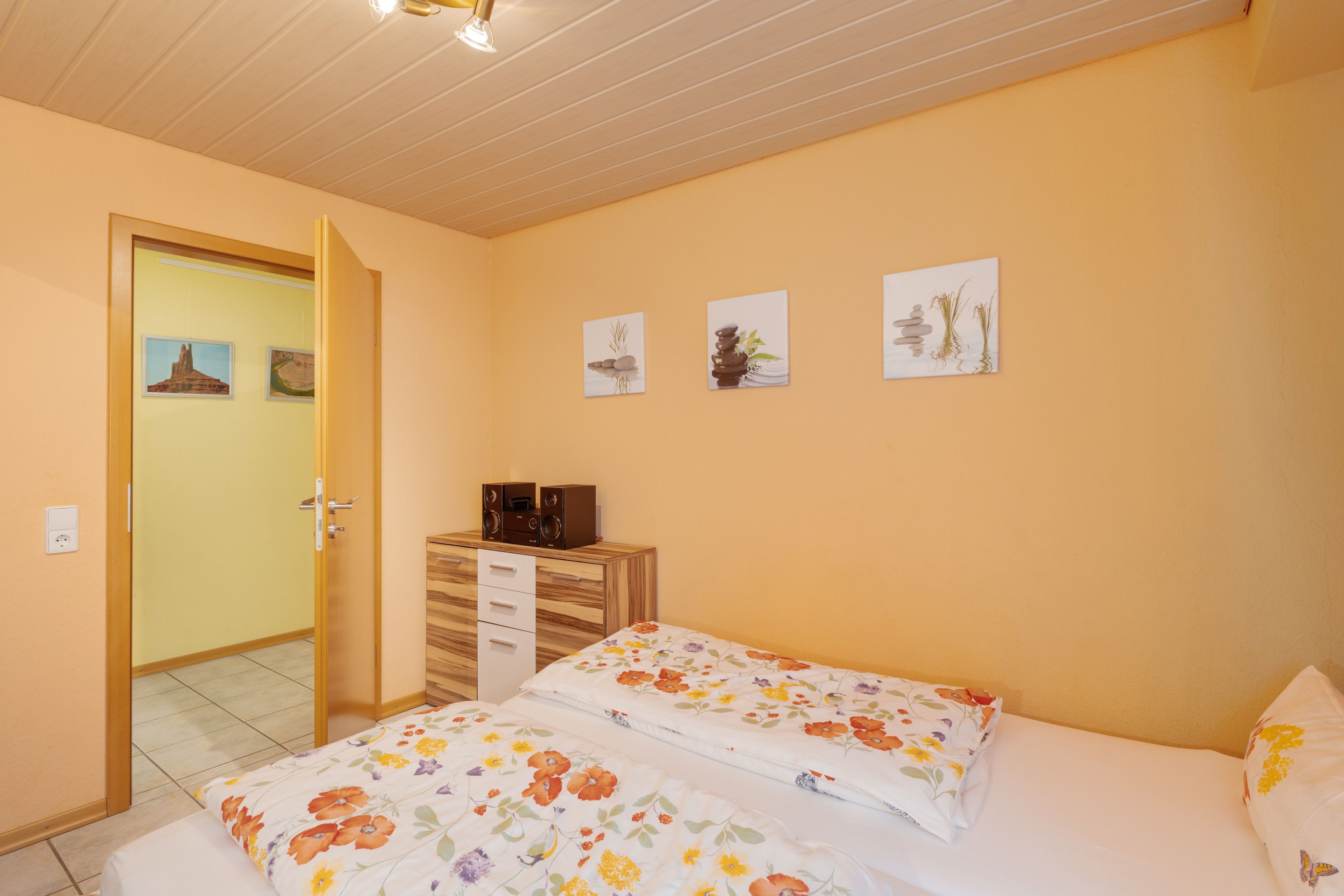 Ein Schlafzimmer mit einem Bett, einer Kommode und einer Tür zu einem anderen Raum.