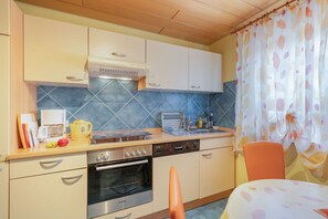 Een kleine keuken met een magnetron, fornuis, oven en een spoelbak.