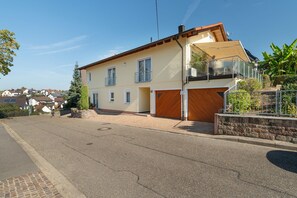Een woonhuis met twee verdiepingen, een garage, een balkon en een heldere lucht.