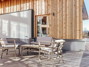Ein Außenbereich mit Tisch und Stühlen, ein Holzhaus mit Balkon und Blick auf die umliegende Landschaft.