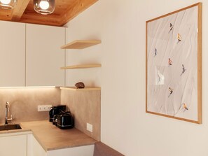 Eine moderne Küche mit Holzböden, einer Kaffeemaschine und einem gerahmten Kunstwerk an der Wand.