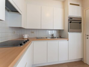 Eine moderne Küche mit weißen Schränken, einer Edelstahl-Spüle und einem Einbauofen.