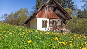 En stuga av trä med ett sluttande tak, en liten veranda och ett fönster med träram.