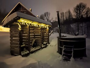 Eine Holzhütte mit verschneitem Dach und einer Veranda mit Lichterketten.