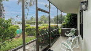 A covered outdoor seating area with a view of a street and greenery. - Charming 2-Bedroom Condo with Heated Pool – Perfect Monthly Retreat (Marco Island)