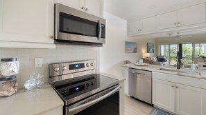 A modern kitchen with stainless steel appliances, white cabinetry, and a built-in dishwasher. - Charming 2-Bedroom Condo with Heated Pool – Perfect Monthly Retreat (Marco Island)