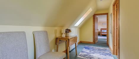 A narrow hallway with a bench, a small table with a vase, and a patterned rug.