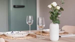 A dining table with plates, glasses, and a vase with flowers. - Saniertes Altbauzimmer an der Karlsaue (Kassel)