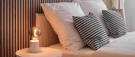 Un dormitorio ordenado con cama, lámpara de noche y una mesita con un objeto decorativo.