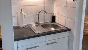 Een keuken met een roestvrijstalen spoelbak, witte kastjes en een marmeren aanrecht.