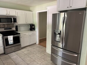 A modern kitchen with stainless steel appliances, white cabinetry, and a tiled floor. - Charming 3-bedroom house in Russellville, close to Tech and power plant. (Russellville)
