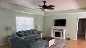 Una sala de estar con sofá, mesa de centro, chimenea y televisor.