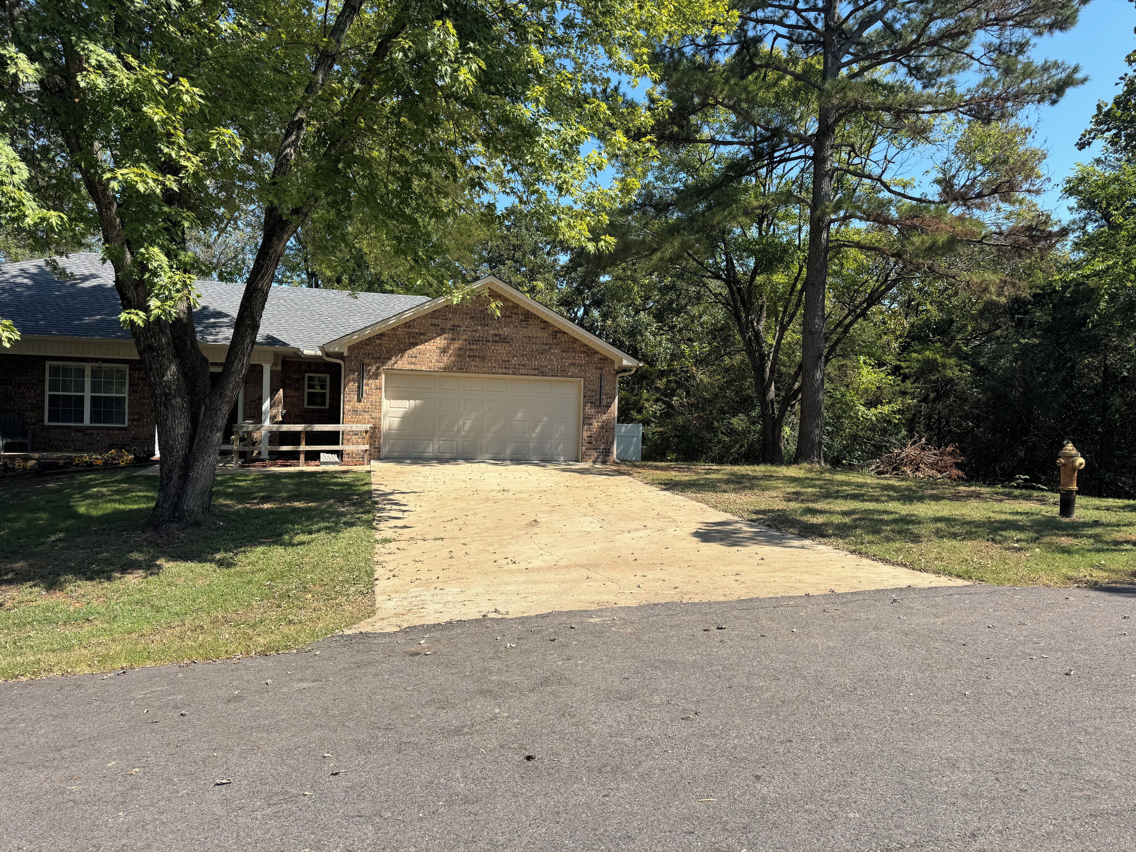 A residential property with a garage, a paved driveway, and a grassy yard.