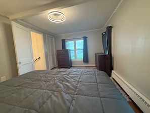Ein Schlafzimmer mit Bett, Schminktisch, Fenster mit Vorhängen und Deckenventilator.