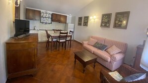 A living room with a sofa, a coffee table, and a dining area with chairs and a table. - Podere Valborgina (Castiglione della Pescaia)