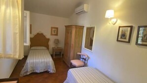 A room with two beds, a chair, a table, and a wardrobe. - Podere Valborgina (Castiglione della Pescaia)