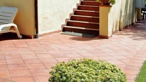 A building with a staircase leading to a door, a lamp post, and a small garden area. - Podere Valborgina (Castiglione della Pescaia)
