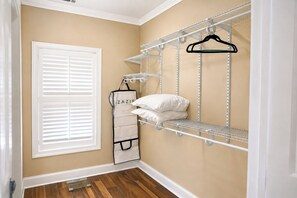 A walk-in closet with metal shelving, a white hanging organizer, and a window with white blinds.