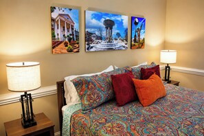A hotel room with a bed, two nightstands, and three wall-mounted pictures.