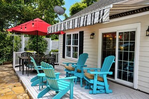 A covered patio with Adirondack chairs, a red umbrella, and a satellite dish.