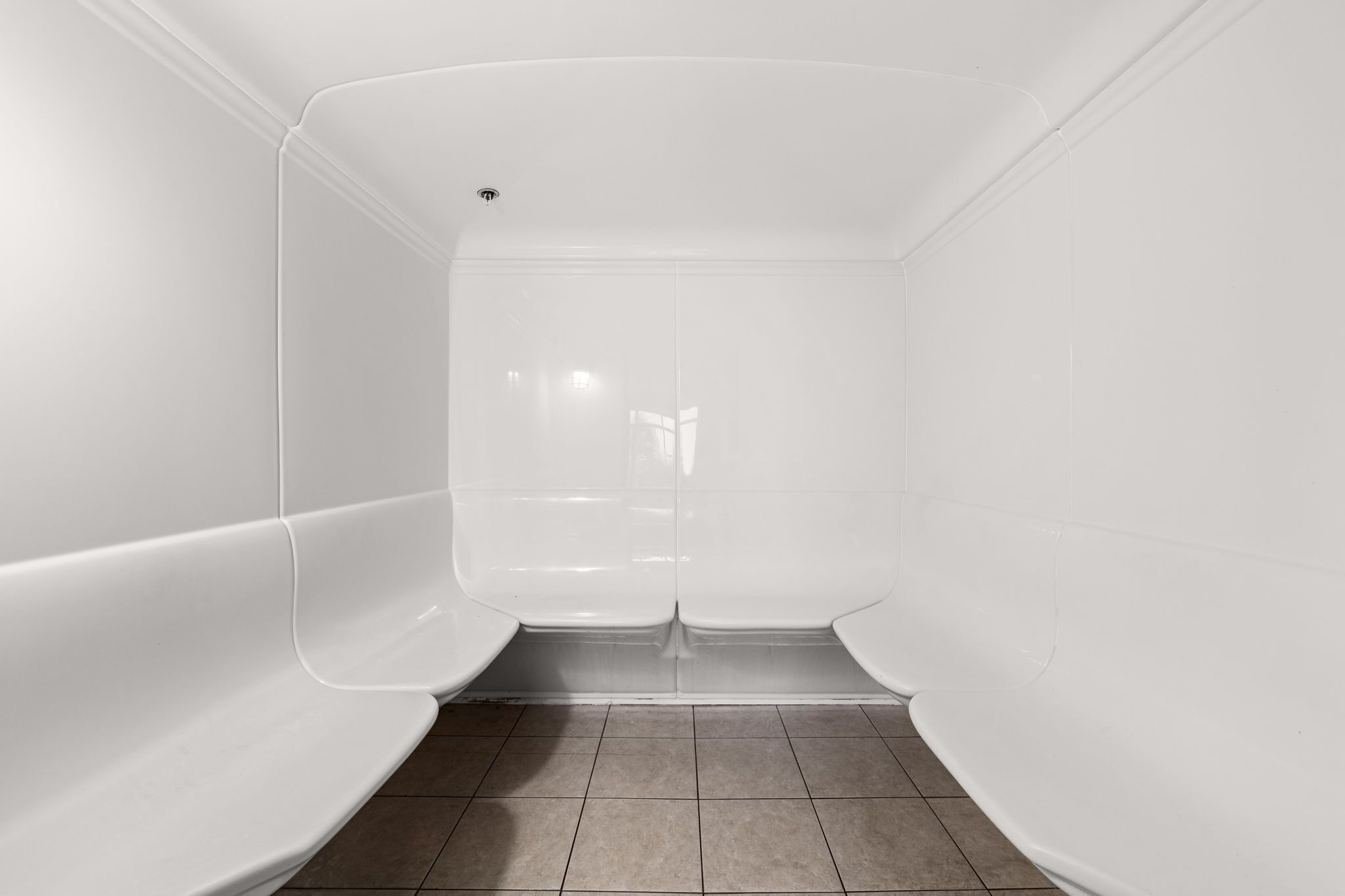 A modern, empty bathroom with white walls and a tiled floor.