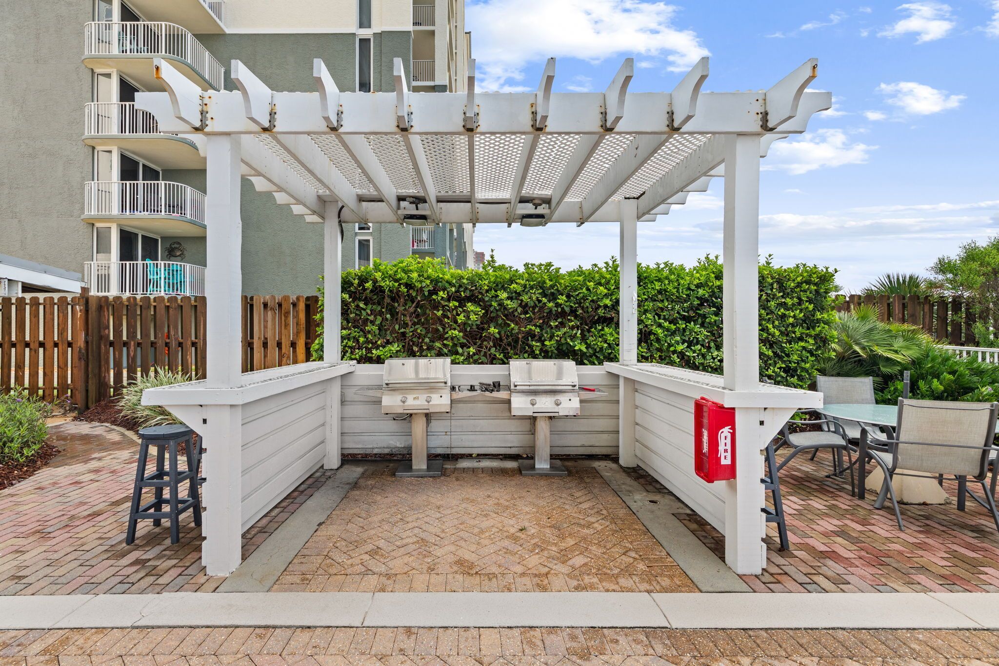 Un patio exterior con pérgola, barbacoa y zona de estar.