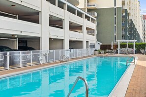 Ein Schwimmbecken mit einer Metallleiter, umgeben von einem weißen Zaun.