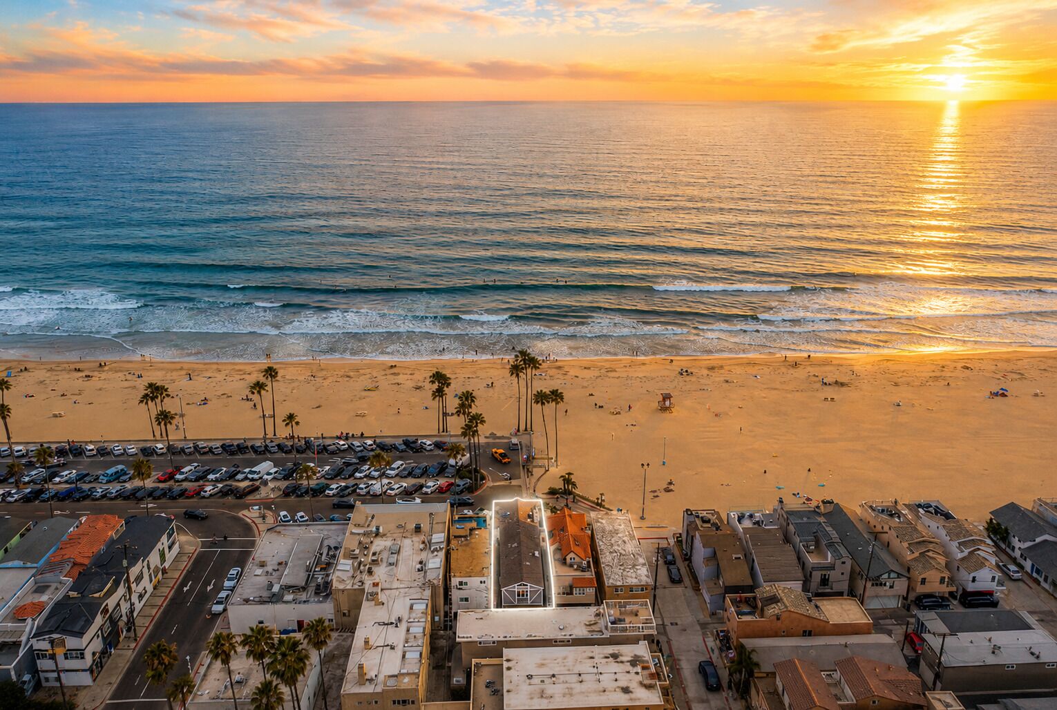 A coastal cityscape with a beach, parking lots, and buildings.