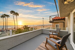 A balcony with a view of the beach, a table, two chairs, and a railing. - Stunning Sunset Views,Great for Families W Parking! (Newport Beach)