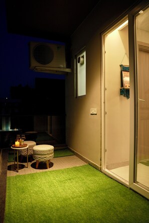 A room with a sliding glass door, a small table with candles, and a wall-mounted air conditioning unit. - Cozy 1-bedroom apartment on golf course roadGurugram near Metro (Gurugram)