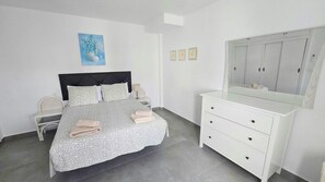 A bedroom with a bed, bedside table, chair, dresser, and a mirror. - Lovely 1-Bedroom Apartment, Pueblo Evita (Benalmádena)