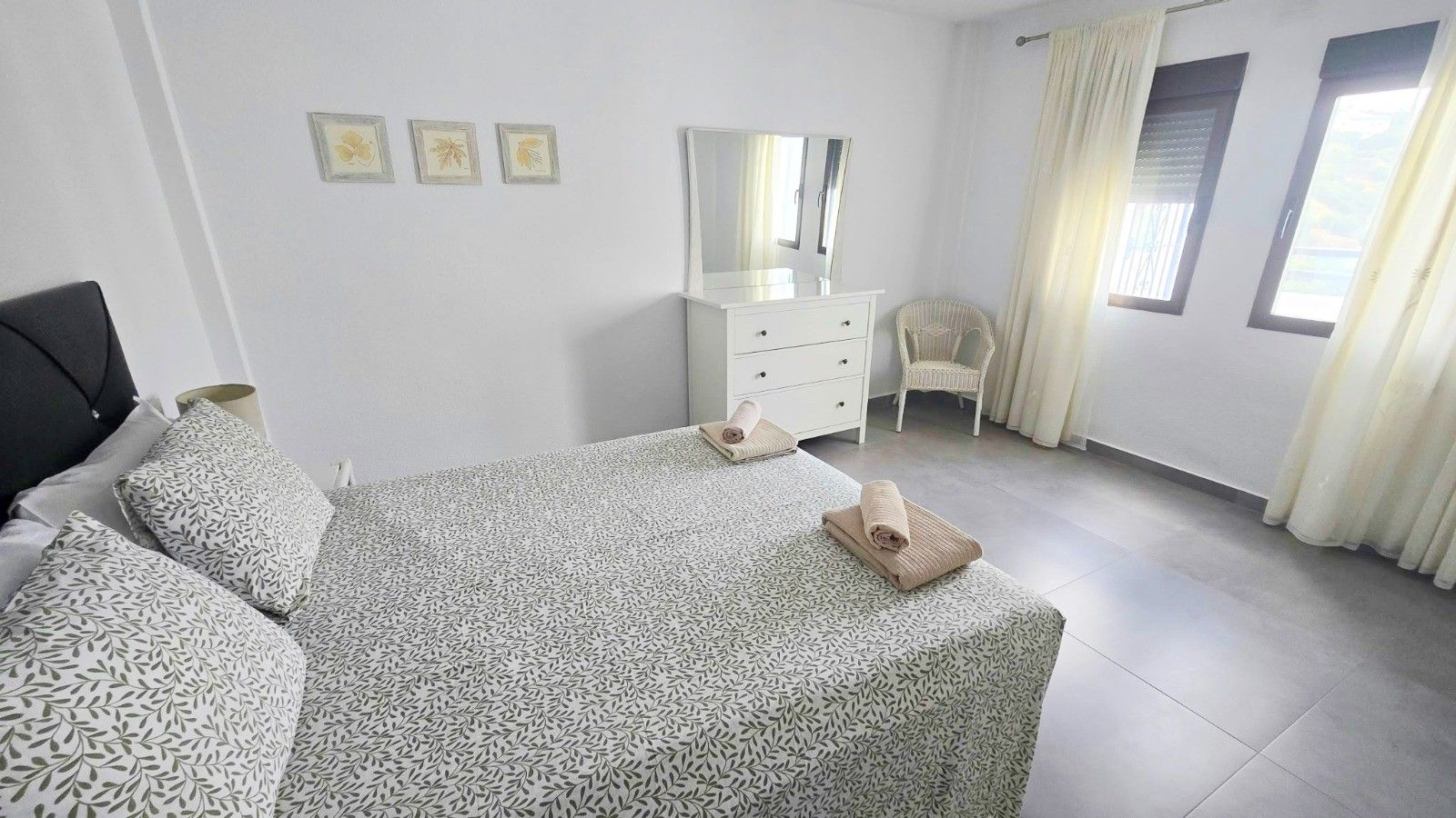 A bedroom with a bed, a dresser, a chair, and a window with curtains.