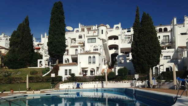 A swimming pool with a clear blue water surface, surrounded by a paved deck area. - Lovely 1-Bedroom Apartment, Pueblo Evita (Benalmádena)
