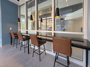 A modern interior with a bar area featuring four bar stools and pendant lighting. - Indoor Spa | Gym | 9th Floor | Urban Oasis (Québec)