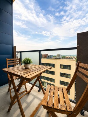 A wooden table and chairs on a balcony with a city view. - Indoor Spa | Gym | 9th Floor | Urban Oasis (Québec)
