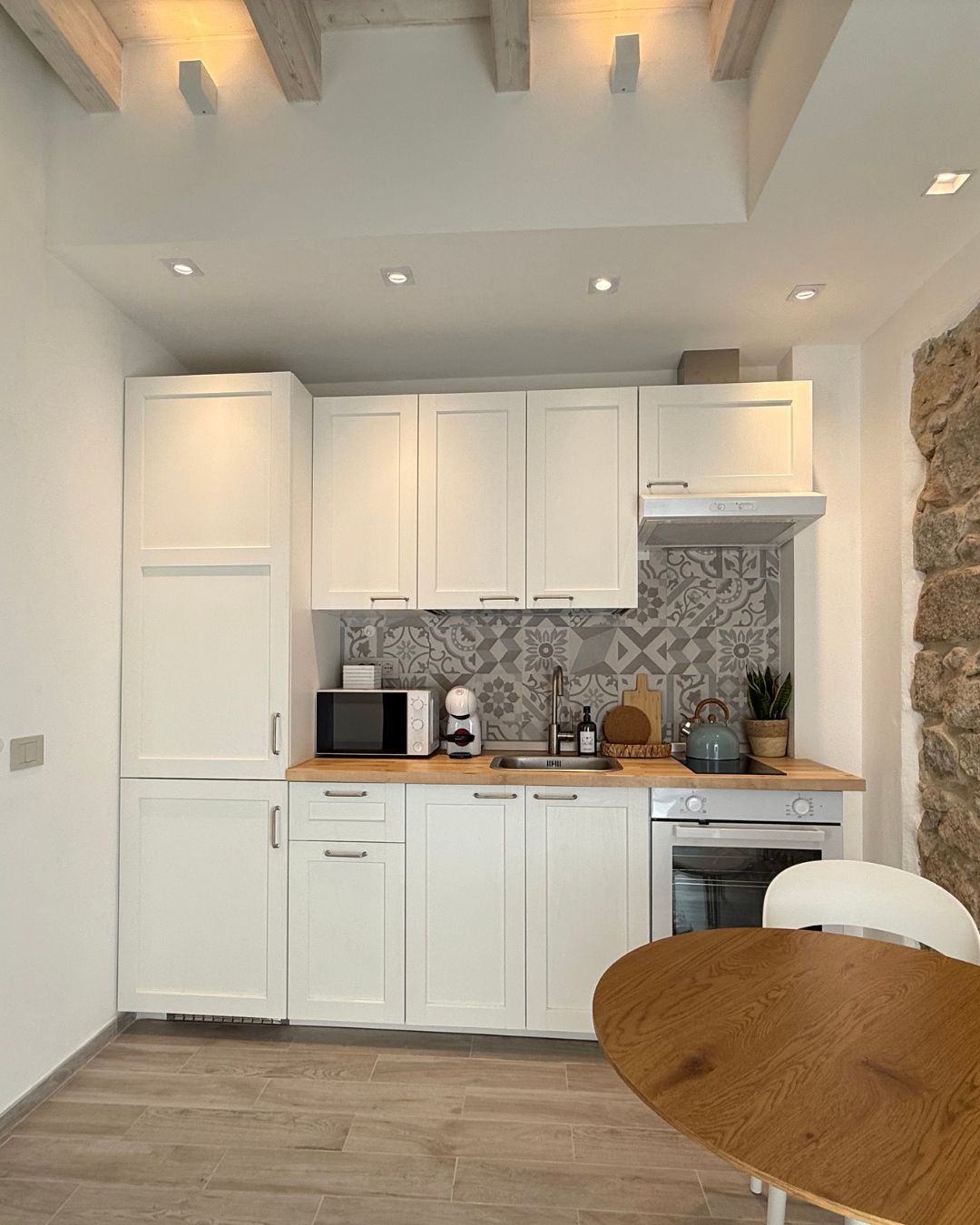 A compact kitchen with white cabinets, a microwave, a toaster, and a sink.