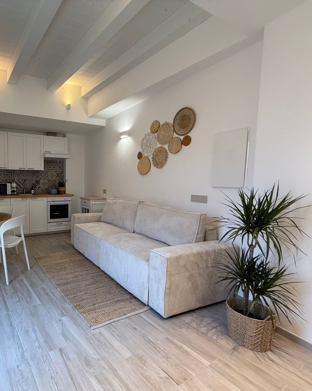Una sala de estar moderna con un sofá, una mesa de comedor y una cocina al fondo.