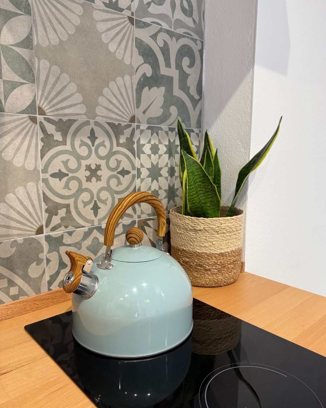 A kettle on a black countertop with a woven basket containing a plant.