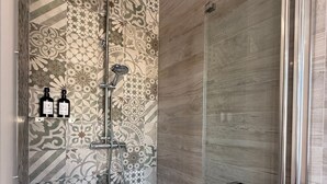 A bathroom with a shower, a bathtub, and a glass-enclosed shower stall.